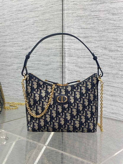 Designer handbag with gold chain and patterned fabric on a reflective surface